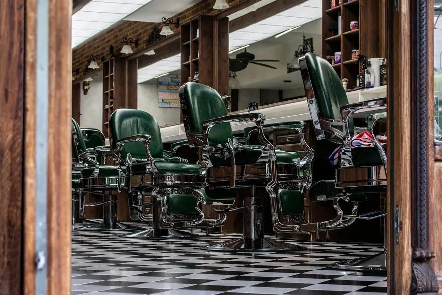 A barber shop website on a phone showing a service menu and an online booking screen