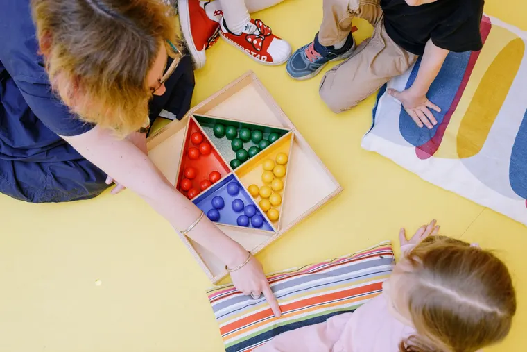 An educator and children around an educational game